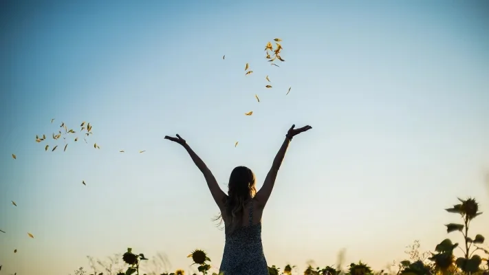 A person celebrating letting go of anxiety by throwing flowers in the air